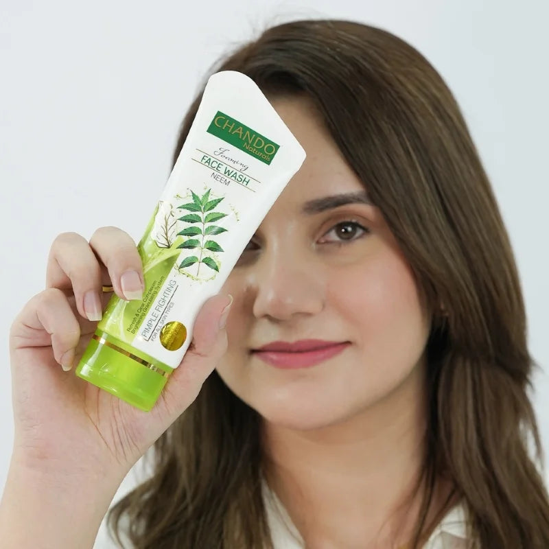 Woman holding a green and white face wash tube with a brand logo.
