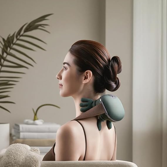 Woman receiving neck and shoulder massage from a green and brown device in a cozy room.