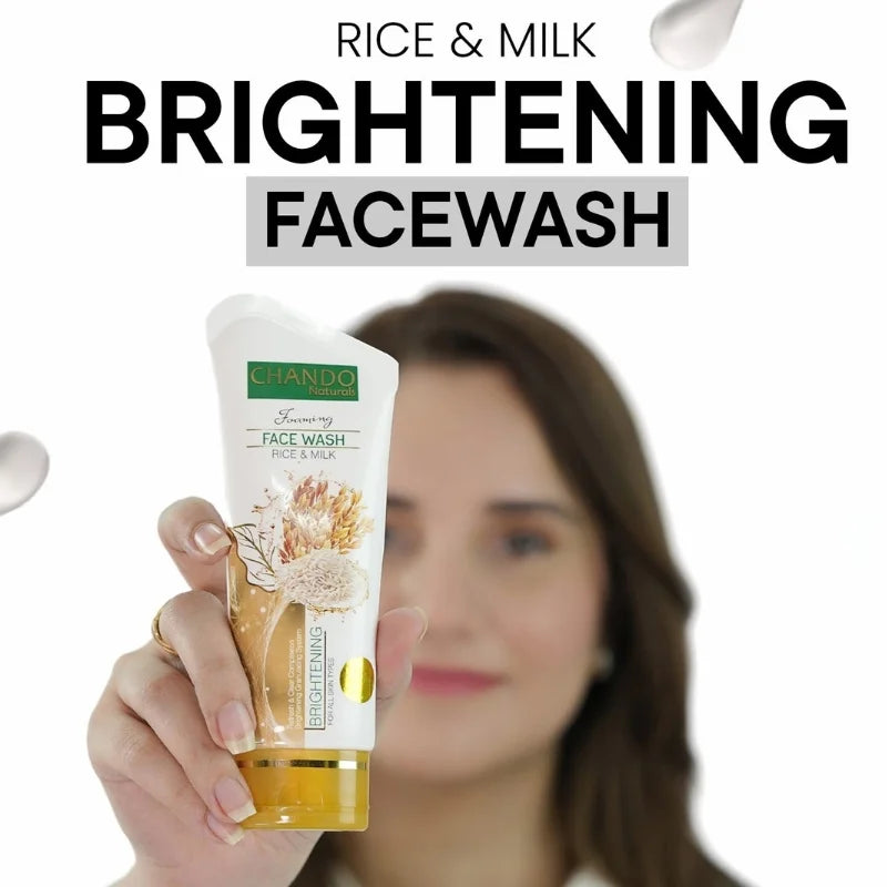 Hand holding a tube of Chando Rice & Milk Brightening Face Wash with a blurred woman in the background.