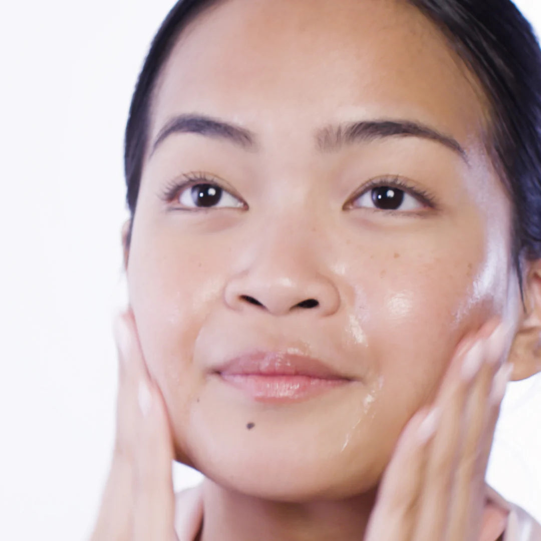 Woman applying cream to her face with a white background