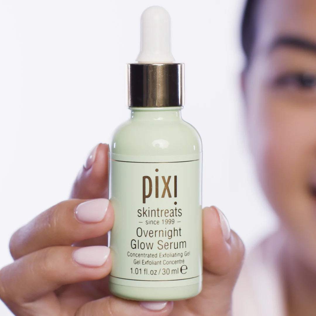 Hand holding a bottle of Pixi Overnight Glow Serum with a blurred background