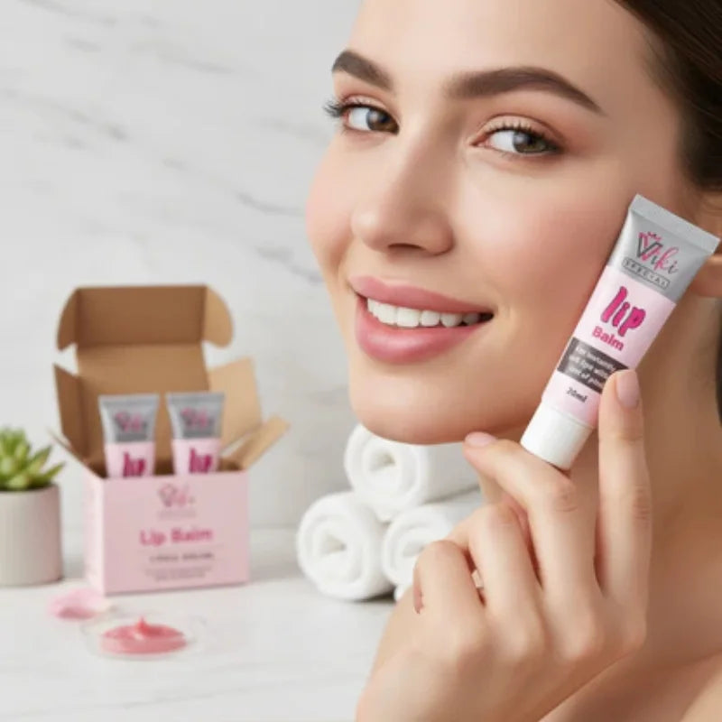 Woman holding a lip balm tube with a box and lip balms in the background