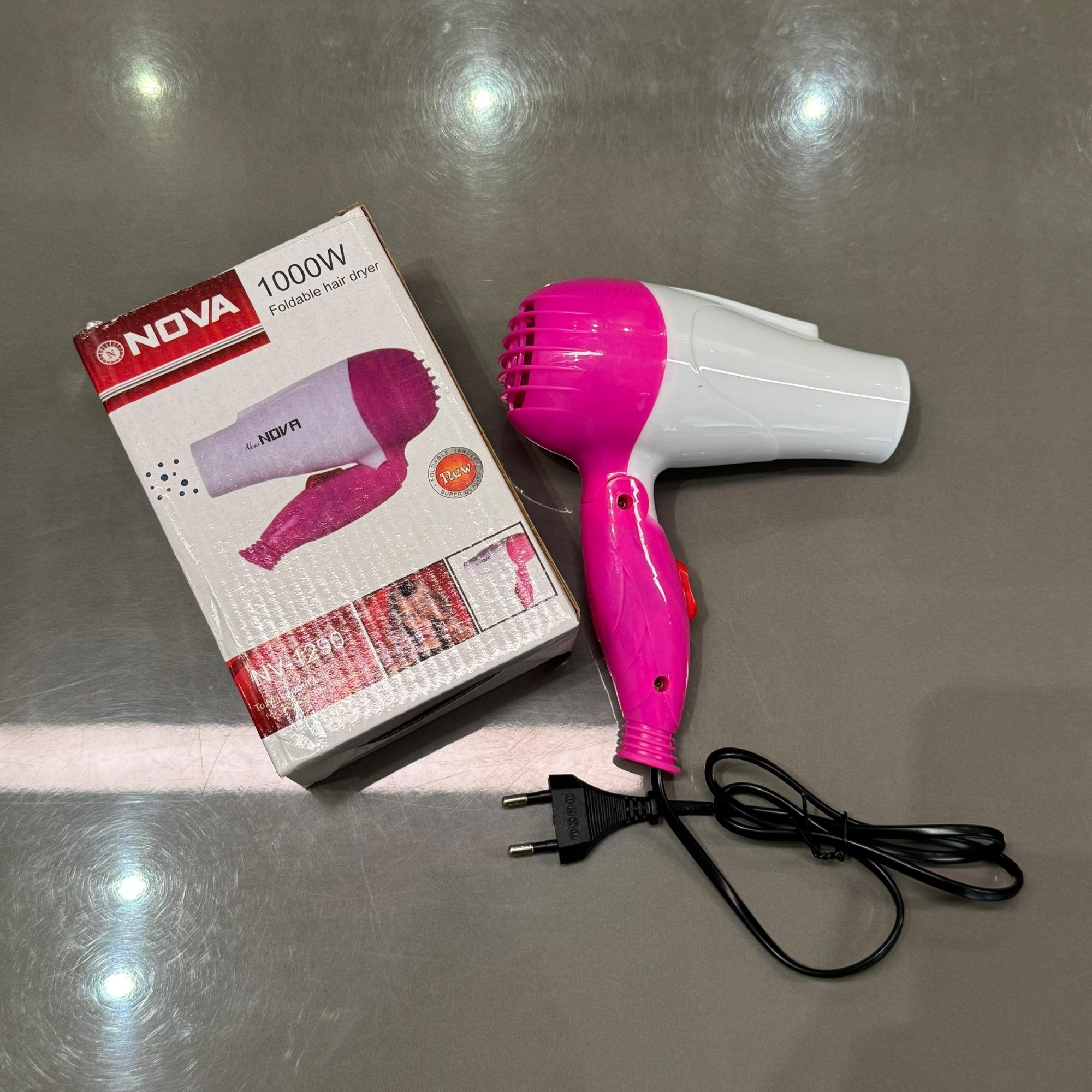 Pink and white hair dryer with packaging on a reflective surface