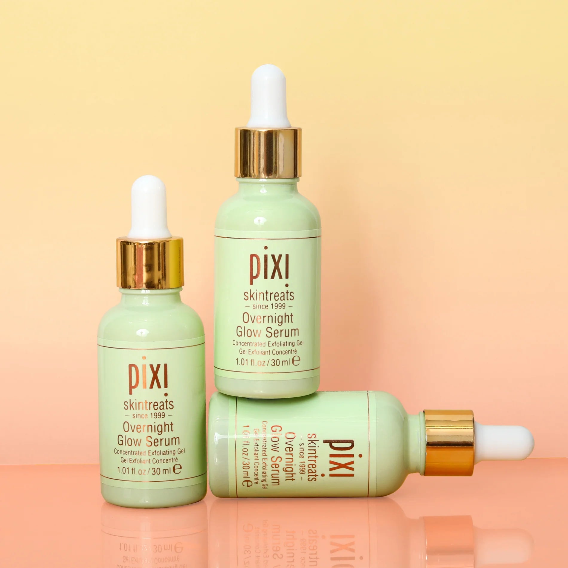 Three bottles of Pixi Overnight Glow Serum on a gradient background