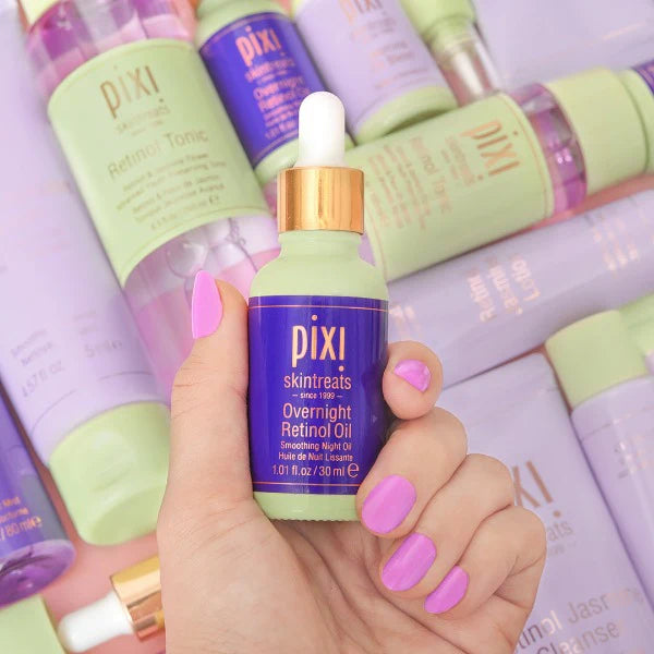 Hand holding a Pixi skincare bottle with other Pixi products in the background
