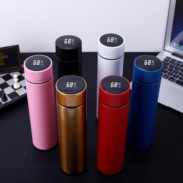 Set of colorful thermos bottles with digital temperature displays on a desk.