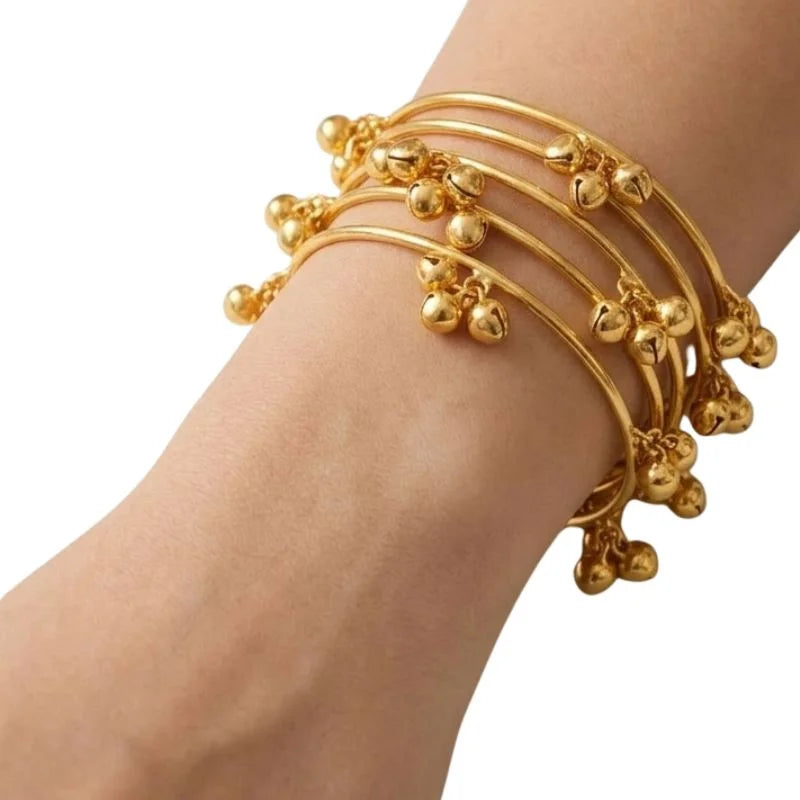 Gold bracelet with bead details on a wrist against a white background